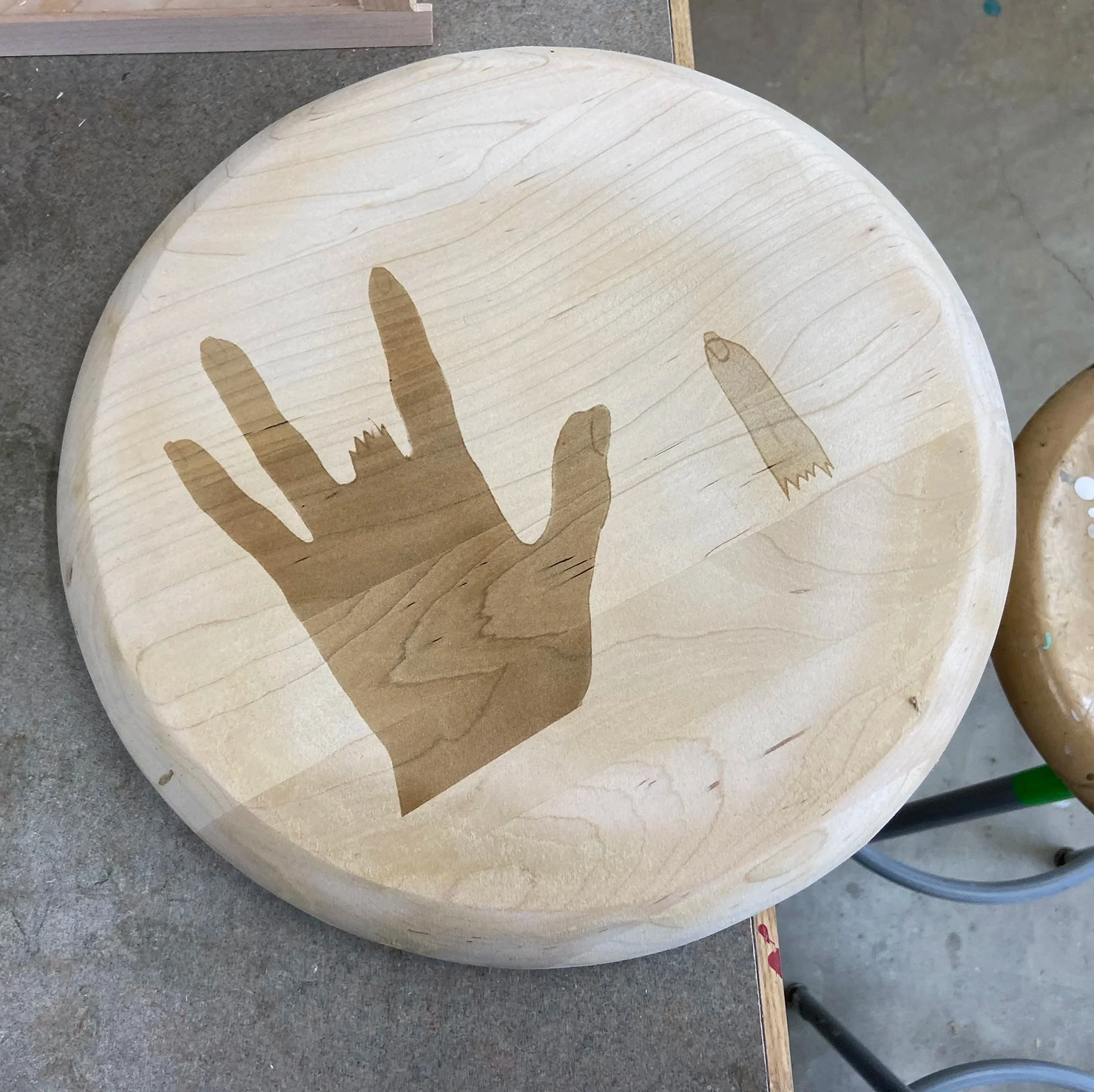 Laser-etched stool with hand and saw drawings